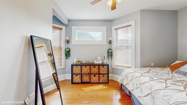 bedroom with light wood-style floors, a ceiling fan, and baseboards