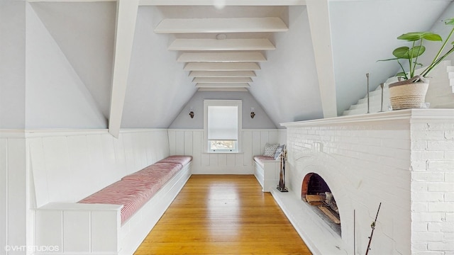 unfurnished living room with wood finished floors, lofted ceiling with beams, and wainscoting