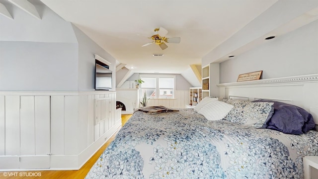 bedroom with visible vents, a ceiling fan, light wood-style flooring, and wainscoting