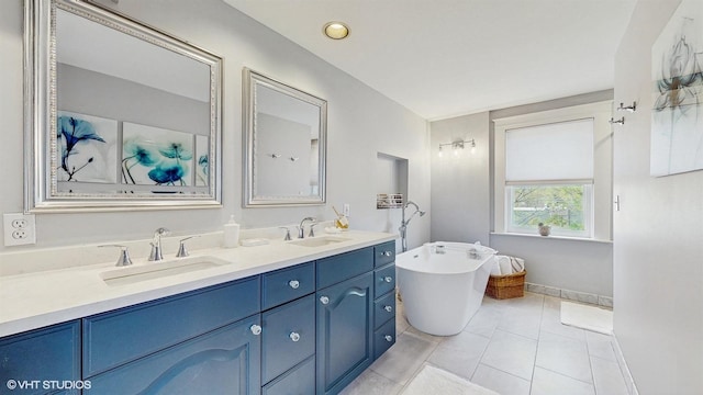 bathroom featuring tile patterned floors, a freestanding tub, double vanity, and a sink