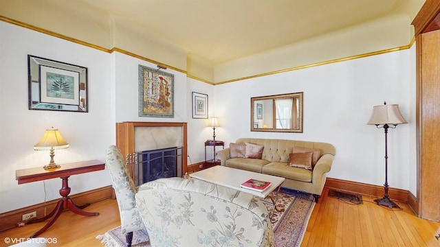 living room with baseboards, hardwood / wood-style floors, and a fireplace