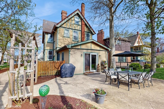 rear view of house featuring fence, a chimney, outdoor dining area, and a patio area