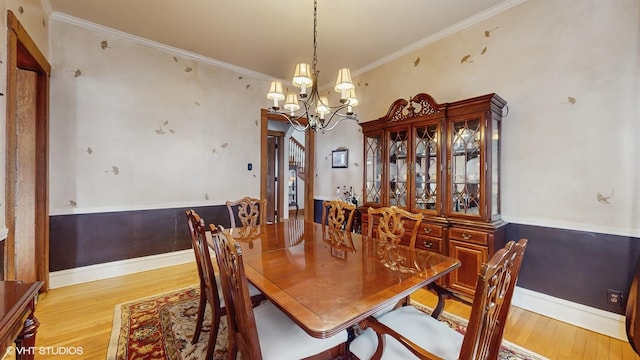 dining space with an inviting chandelier, ornamental molding, light wood-style flooring, and baseboards