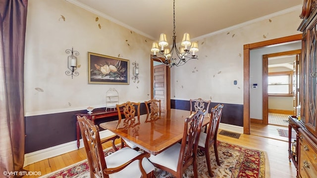 dining space featuring crown molding, a chandelier, visible vents, light wood-style floors, and baseboards