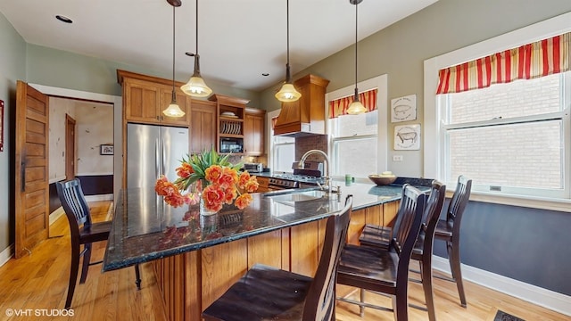 kitchen with a breakfast bar area, a sink, brown cabinetry, and plenty of natural light