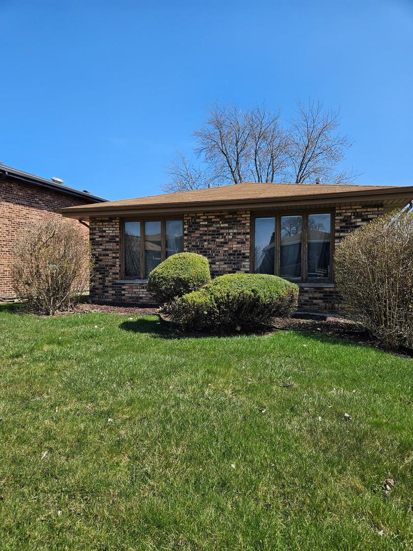 back of property featuring a lawn and brick siding
