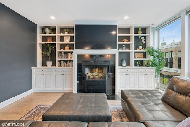 living area with baseboards, a tiled fireplace, recessed lighting, and wood finished floors