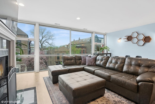living area with a warm lit fireplace, recessed lighting, and expansive windows