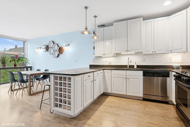 kitchen with expansive windows, stainless steel appliances, tasteful backsplash, and a sink