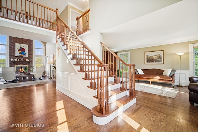 stairway featuring wainscoting, a fireplace, a decorative wall, and wood finished floors