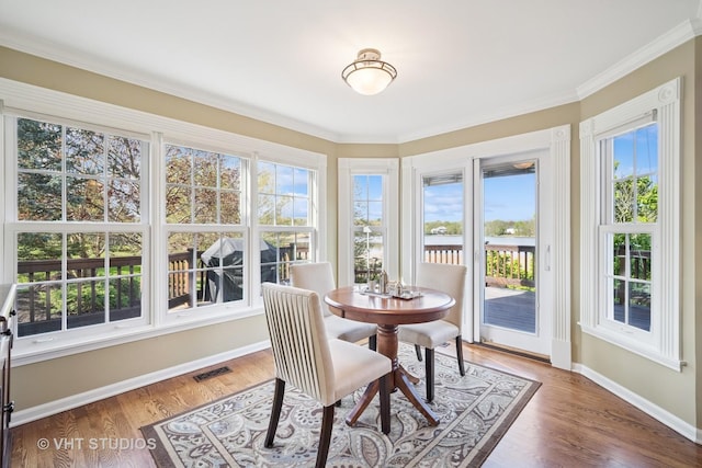 sunroom with baseboards, plenty of natural light, ornamental molding, and visible vents