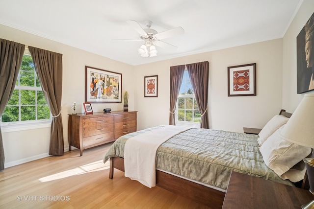 bedroom with baseboards, ceiling fan, ornamental molding, and light wood-style flooring