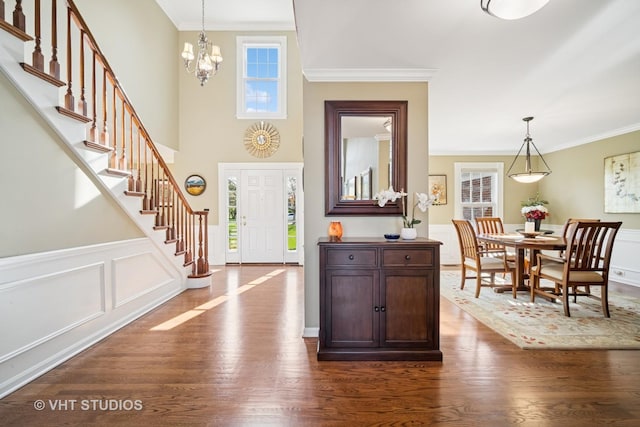 foyer entrance with crown molding, a chandelier, dark wood-style floors, and stairway