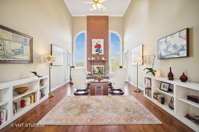 interior space with ceiling fan, a fireplace, dark wood-style flooring, and a towering ceiling
