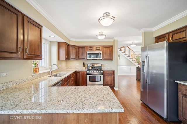 kitchen featuring dark wood-style flooring, crown molding, appliances with stainless steel finishes, light stone countertops, and a sink