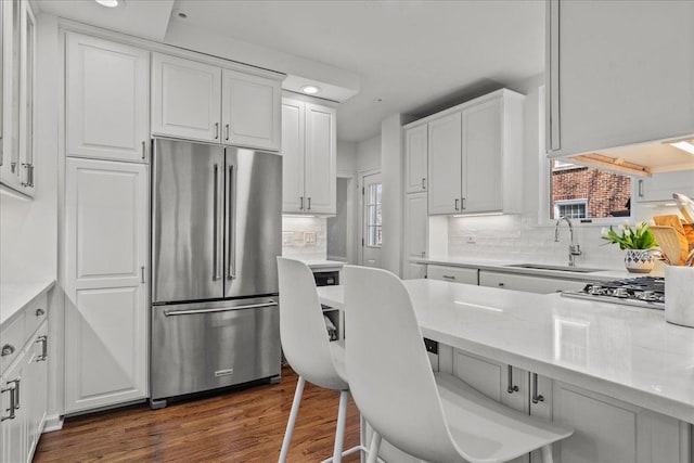 2341 Lincolnwood Dr, Evanston, IL 60201 - kitchen featuring white cabinets, stainless steel appliances, a sink, tasteful backsplash, and dark wood-style flooring