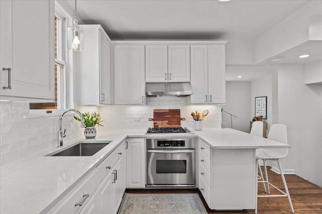 2341 Lincolnwood Dr, Evanston, IL 60201 - kitchen with white cabinets, under cabinet range hood, a sink, a peninsula, and stainless steel oven