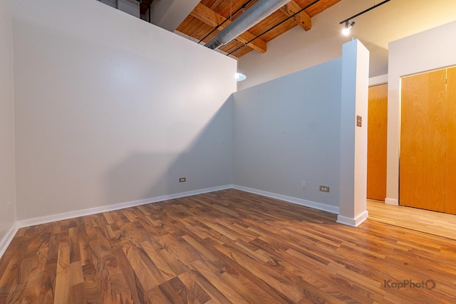 additional living space with wood finished floors, beam ceiling, and baseboards
