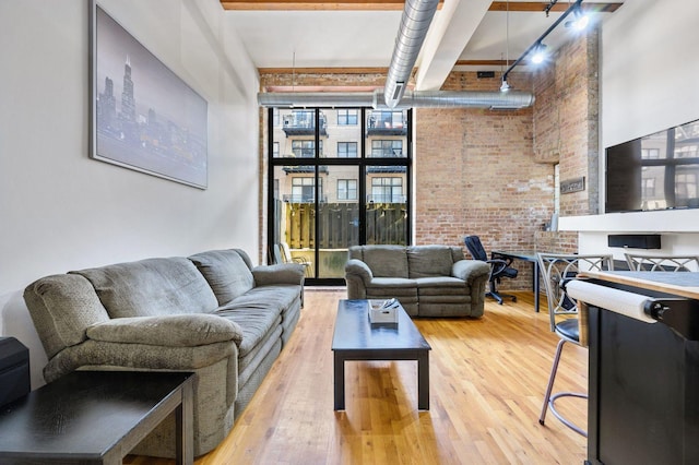 living area featuring brick wall, wood finished floors, and a towering ceiling