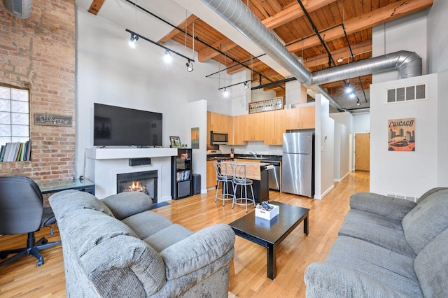 living room featuring rail lighting, wooden ceiling, a high ceiling, beam ceiling, and visible vents