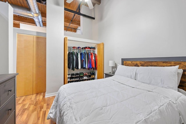 bedroom with a towering ceiling, wood finished floors, a closet, beam ceiling, and wood ceiling