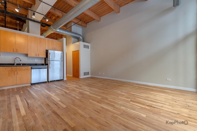 kitchen featuring dark countertops, a high ceiling, appliances with stainless steel finishes, and visible vents