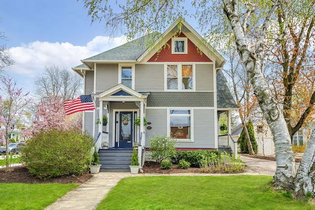 view of front of home with a shingled roof and a front yard