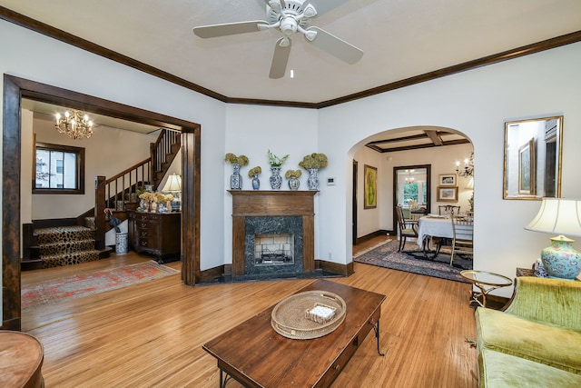 living room with wood finished floors, stairway, arched walkways, ceiling fan with notable chandelier, and a premium fireplace