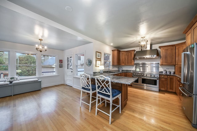 kitchen featuring appliances with stainless steel finishes, exhaust hood, a peninsula, and a chandelier