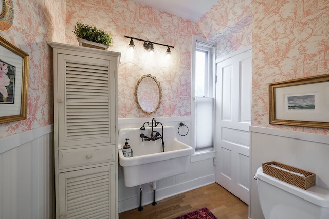 bathroom featuring wainscoting, wood finished floors, toilet, and wallpapered walls