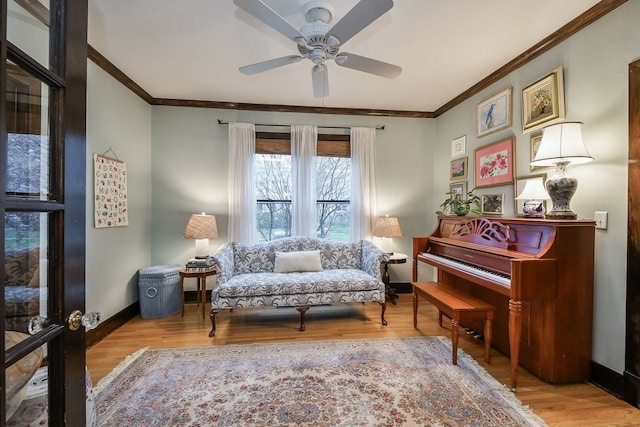 sitting room featuring crown molding, baseboards, ceiling fan, and wood finished floors