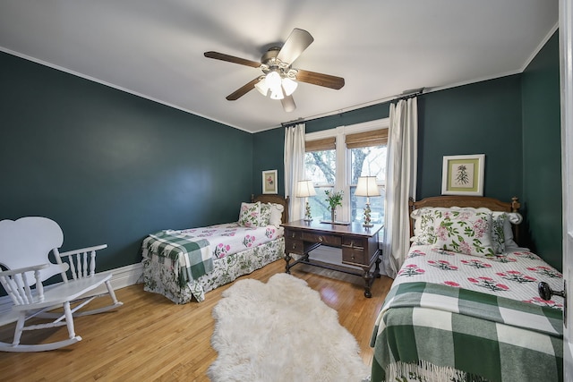 bedroom featuring baseboards, ceiling fan, ornamental molding, and wood finished floors