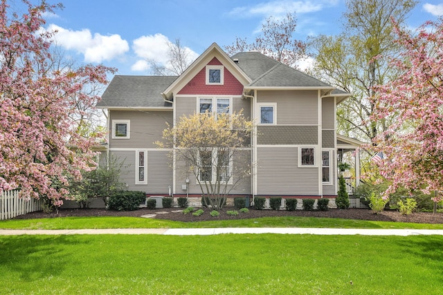 rear view of house featuring a yard, fence, and roof with shingles