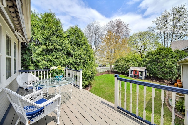 wooden deck with a storage shed, a fenced backyard, an outbuilding, outdoor dining area, and a lawn
