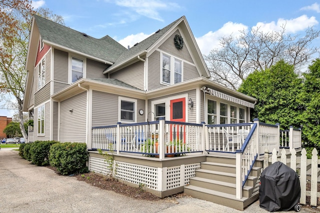 rear view of property with a shingled roof and a wooden deck