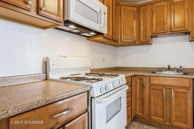 7010 S E End Ave Unit 4, Chicago, IL 60649 - kitchen with a sink, light tile patterned floors, white appliances, brown cabinetry, and light countertops