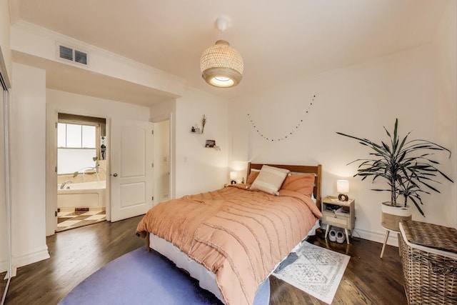 bedroom with visible vents, dark wood finished floors, and ensuite bathroom