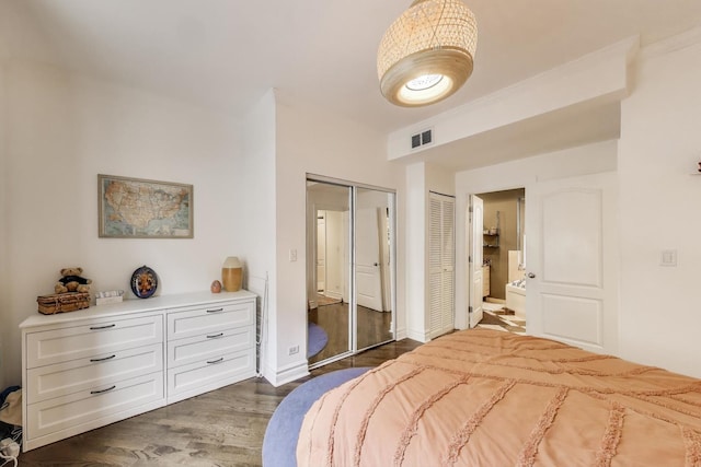 bedroom featuring dark wood-style flooring, baseboards, visible vents, and ensuite bath