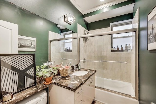 bathroom with a healthy amount of sunlight, vanity, crown molding, and combined bath / shower with glass door