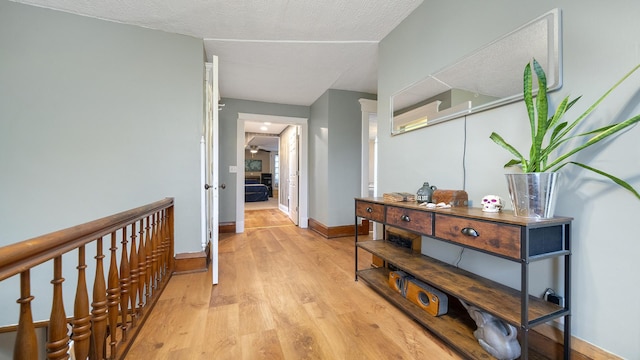 hall featuring light wood-style flooring and baseboards