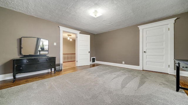 bedroom featuring baseboards, wood finished floors, a textured ceiling, and carpet floors