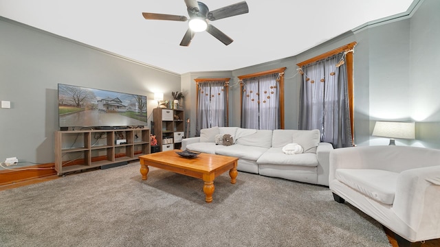carpeted living area with crown molding and a ceiling fan
