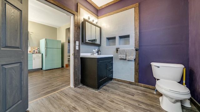 bathroom featuring toilet, vanity, wood finished floors, and baseboards
