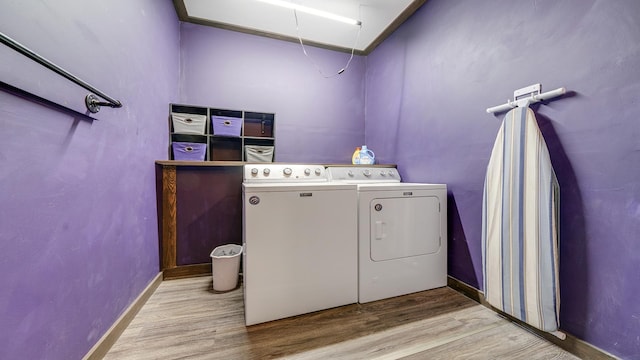 washroom with wood finished floors, attic access, washing machine and dryer, baseboards, and laundry area