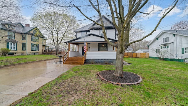 traditional style home featuring a front lawn, fence, and covered porch