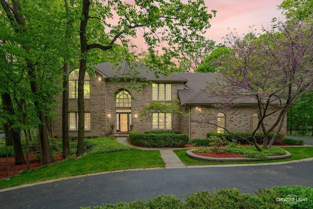 view of front of property featuring brick siding and a yard