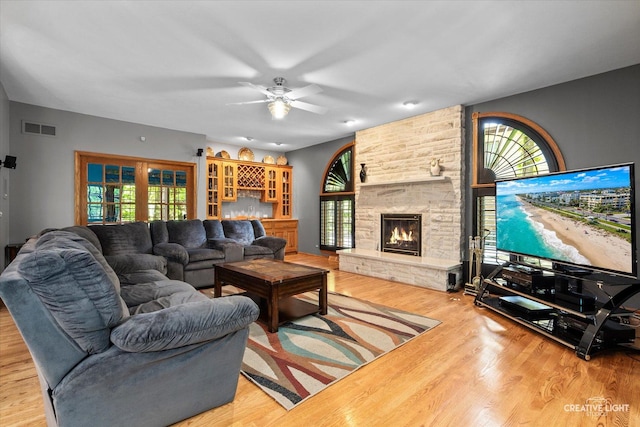 living area with ceiling fan, wood finished floors, and a stone fireplace