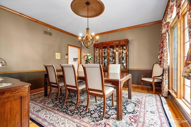 dining area featuring a chandelier, wood finished floors, ornamental molding, and baseboards