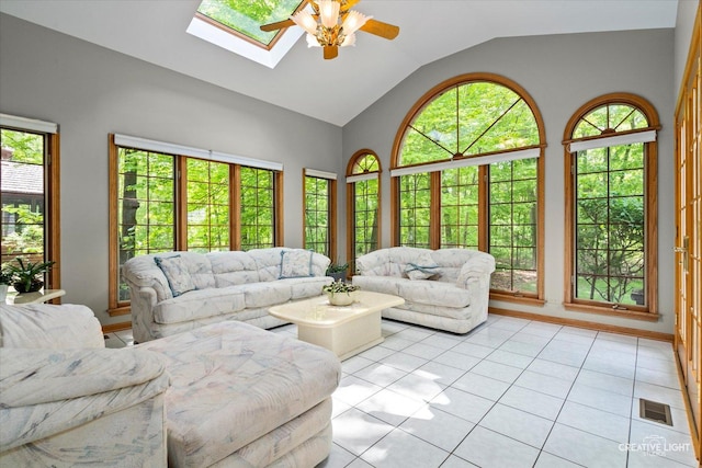 living room with a ceiling fan, vaulted ceiling, a skylight, and light tile patterned flooring