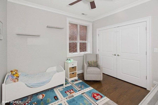 bedroom with a closet, wood finished floors, ornamental molding, visible vents, and ceiling fan